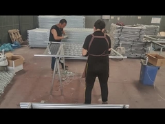 작업자들이 체인 링크 울타리와 프레임 튜브를 연결하기 위해 철사를 사용하고 있습니다.